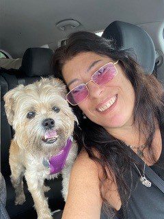 A woman and her dog in the back of a car.