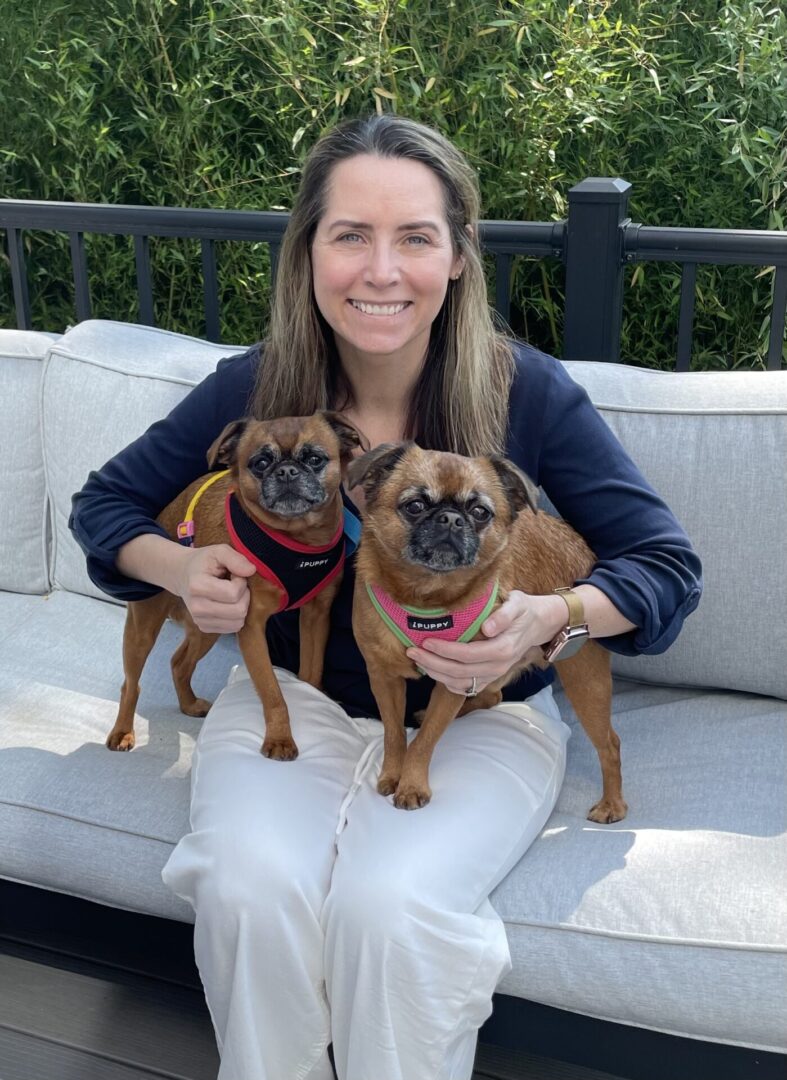 Kirk 3886 and Patrick 3887 HE Woman sitting with two small dogs outdoors.