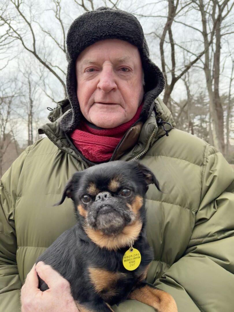 Man holding a small black and tan dog.